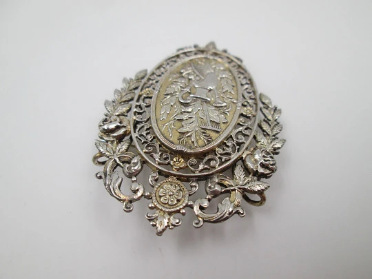 Broche mujer. Metal blanco y dorado. Cerco calado floreado. Cántaro y cesta. 1950