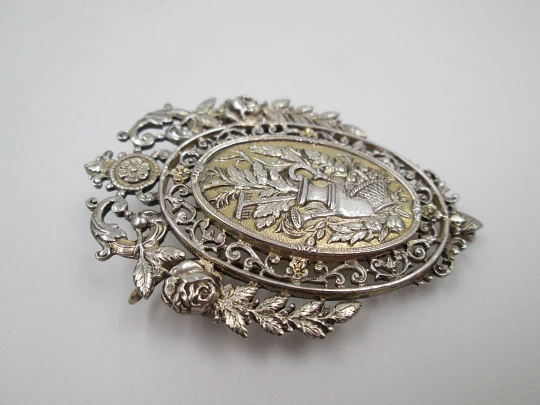 Broche mujer. Metal blanco y dorado. Cerco calado floreado. Cántaro y cesta. 1950