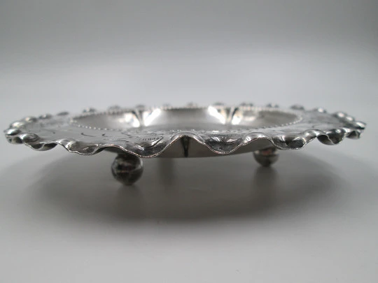 Ornate sterling silver salver. Chiseled floral motifs. Three legs and irregular edge. 1970's