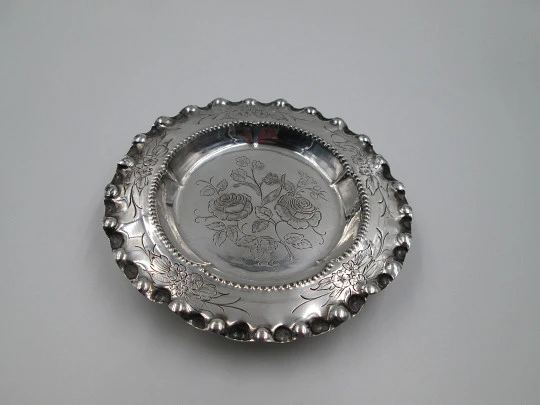 Ornate sterling silver salver. Chiseled floral motifs. Three legs and irregular edge. 1970's