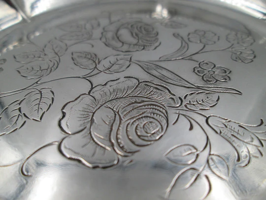 Ornate sterling silver salver. Chiseled floral motifs. Three legs and irregular edge. 1970's