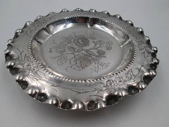 Ornate sterling silver salver. Chiseled floral motifs. Three legs and irregular edge. 1970's