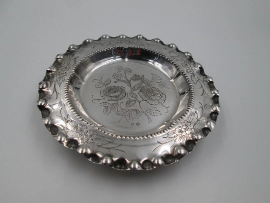 Ornate sterling silver salver. Chiseled floral motifs. Three legs and irregular edge. 1970's