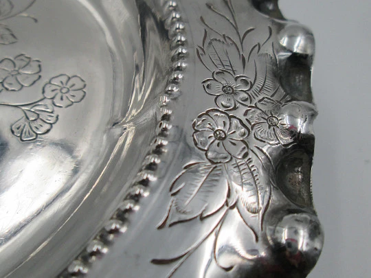 Ornate sterling silver salver. Chiseled floral motifs. Three legs and irregular edge. 1970's