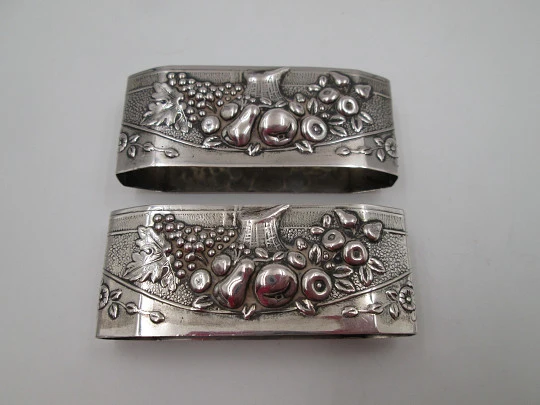 Two napkin rings. Sterling silver. Basket with fruits. Floral motifs. Europe. 1950's